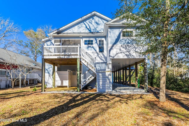 rear view of property with a sunroom, a wooden deck, stairs, and a yard