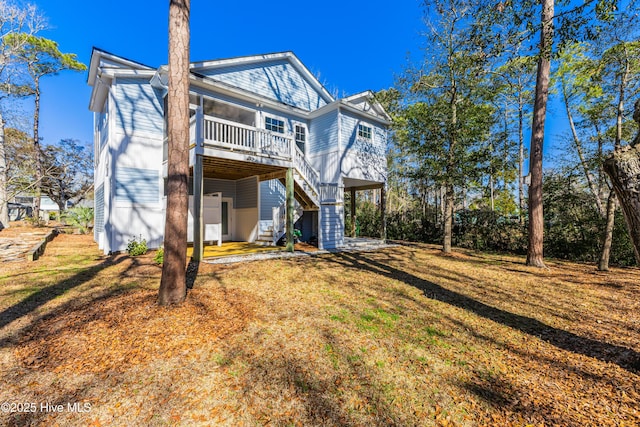 back of house with a yard, a carport, and stairs