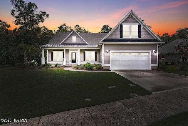 craftsman-style home with a porch, a garage, and a lawn