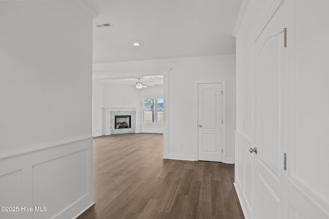 hallway with ornamental molding, visible vents, a decorative wall, and dark wood-style floors