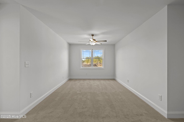 empty room with a ceiling fan, light carpet, and baseboards