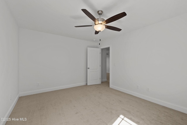 empty room featuring light carpet, a ceiling fan, and baseboards