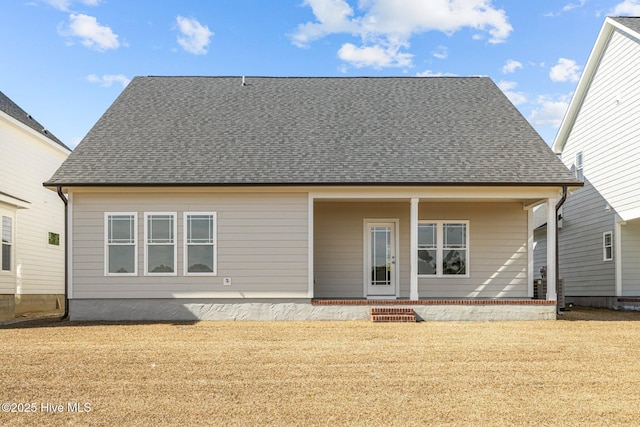 back of property featuring roof with shingles and a yard