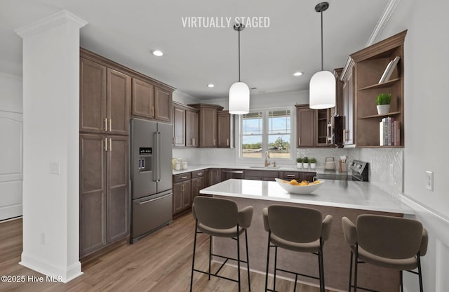 kitchen featuring light wood finished floors, visible vents, appliances with stainless steel finishes, crown molding, and a sink