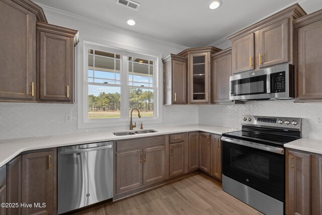 kitchen with dark wood-style flooring, crown molding, stainless steel appliances, a sink, and a peninsula