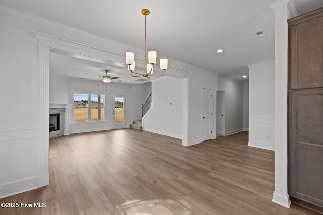 unfurnished living room with stairs, a stone fireplace, light wood finished floors, and ornamental molding