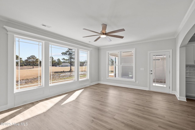 interior space with ceiling fan, baseboards, crown molding, and wood finished floors