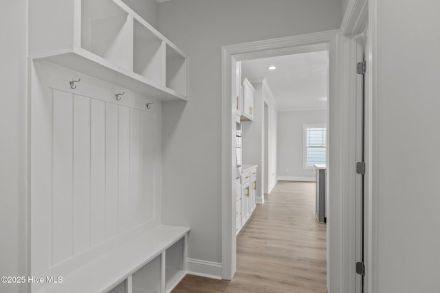 mudroom featuring light wood finished floors and baseboards