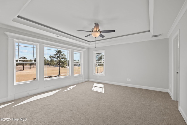 carpeted spare room with a tray ceiling, visible vents, ornamental molding, ceiling fan, and baseboards