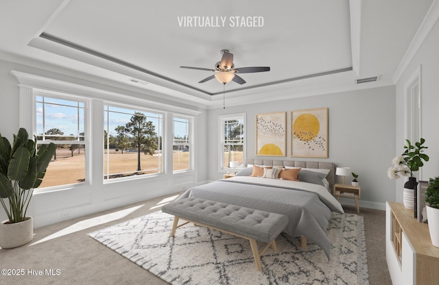 bedroom with carpet floors, a tray ceiling, visible vents, and a ceiling fan