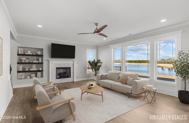 living room featuring a stone fireplace, wood finished floors, and a healthy amount of sunlight