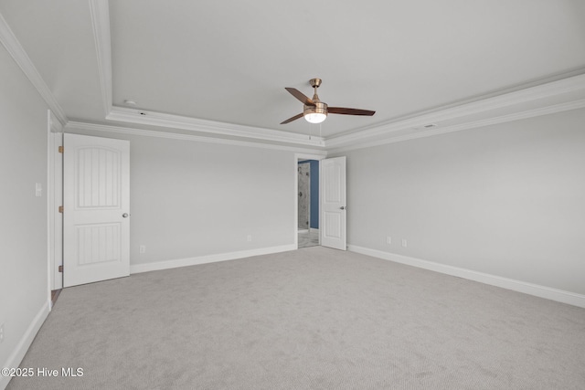 empty room with a tray ceiling, ornamental molding, a ceiling fan, light carpet, and baseboards