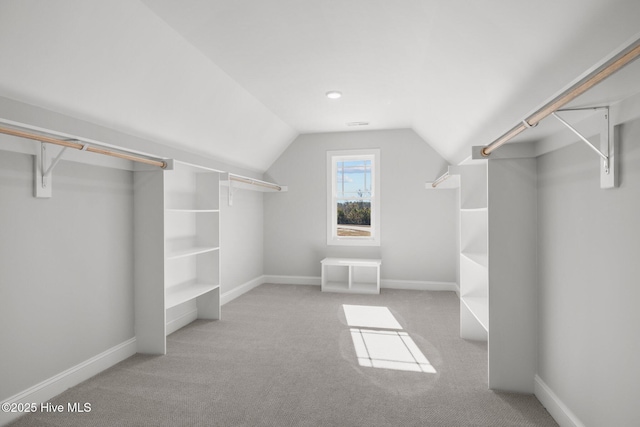 walk in closet with light carpet and vaulted ceiling