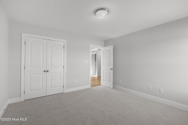 unfurnished bedroom featuring a closet, light colored carpet, and baseboards