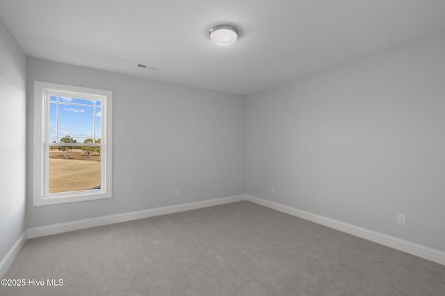 unfurnished room featuring carpet floors, visible vents, and baseboards