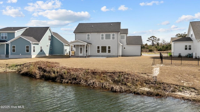 rear view of house featuring a residential view, a water view, and fence