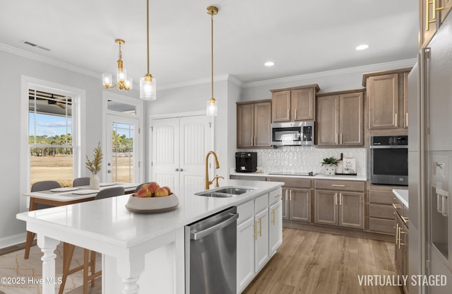 kitchen with decorative backsplash, appliances with stainless steel finishes, decorative light fixtures, light countertops, and a sink