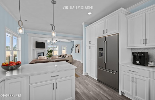 kitchen with light countertops, ornamental molding, open floor plan, white cabinets, and high quality fridge