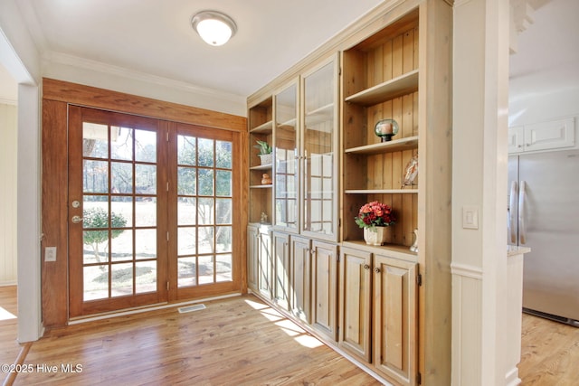 doorway to outside featuring crown molding, light hardwood / wood-style floors, and built in features