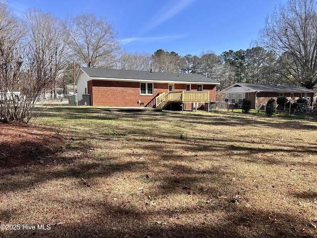 613 Sexton Ave, Zebulon, NC 27597 - back of property featuring a lawn, a deck, fence, and brick siding