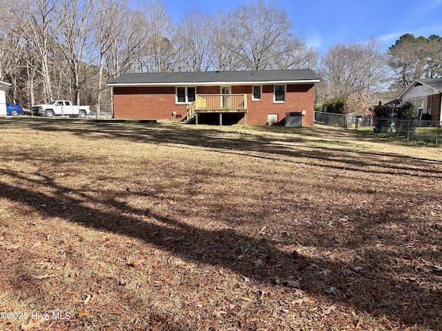 613 Sexton Ave, Zebulon, NC 27597 - rear view of house with brick siding, a deck, fence, and a lawn