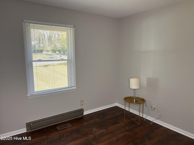 613 Sexton Ave, Zebulon, NC 27597 - empty room featuring dark wood-style flooring, baseboards, a textured ceiling, visible vents, and a baseboard radiator