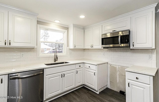 kitchen with appliances with stainless steel finishes, sink, dark hardwood / wood-style flooring, white cabinets, and light stone countertops