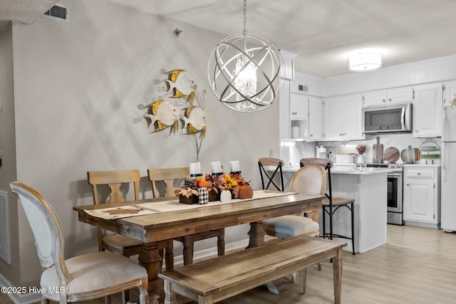 dining space with a chandelier and light hardwood / wood-style floors