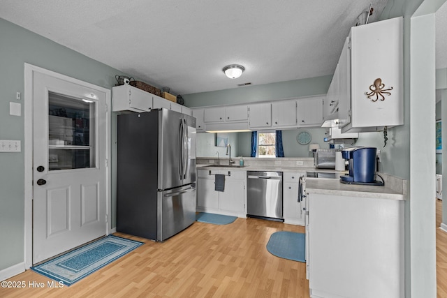 1810 Paulette Rd, Morehead City, NC 28557 - kitchen featuring stainless steel appliances, light wood-type flooring, light countertops, a sink, and a textured ceiling