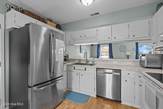 1810 Paulette Rd, Morehead City, NC 28557 - kitchen with stainless steel appliances, a sink, light countertops, a textured ceiling, and light wood-style floors