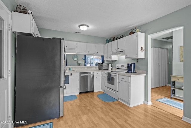1810 Paulette Rd, Morehead City, NC 28557 - kitchen with stainless steel appliances, under cabinet range hood, light wood-type flooring, light countertops, and white cabinets