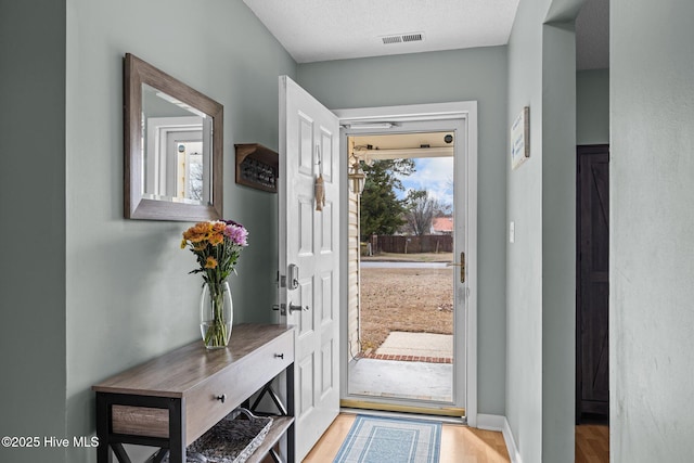 doorway to outside featuring light hardwood / wood-style flooring and a textured ceiling