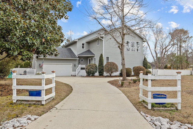 traditional-style home with an attached garage, a shingled roof, fence, and concrete driveway