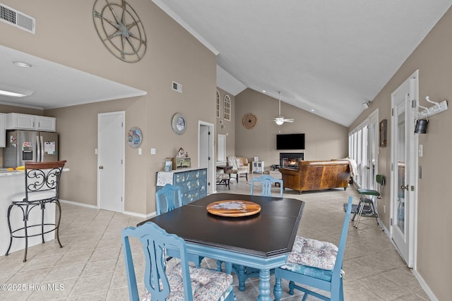 806 Lord Granville Dr, Morehead City, NC 28557 - dining room with a warm lit fireplace, light tile patterned floors, a ceiling fan, baseboards, and high vaulted ceiling