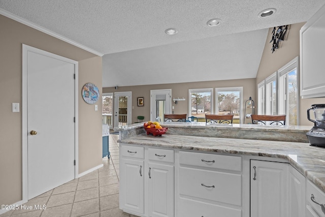 806 Lord Granville Dr, Morehead City, NC 28557 - kitchen with a textured ceiling, white cabinetry, light tile patterned floors, ornamental molding, and vaulted ceiling