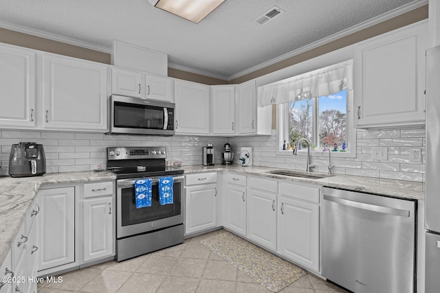 806 Lord Granville Dr, Morehead City, NC 28557 - kitchen featuring stainless steel appliances, a sink, white cabinetry, crown molding, and a textured ceiling