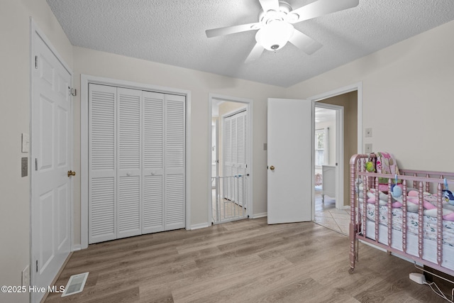 806 Lord Granville Dr, Morehead City, NC 28557 - bedroom with wood finished floors, a textured ceiling, ceiling fan, and two closets
