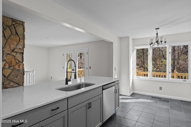 kitchen with a sink, light countertops, stainless steel dishwasher, gray cabinets, and decorative light fixtures