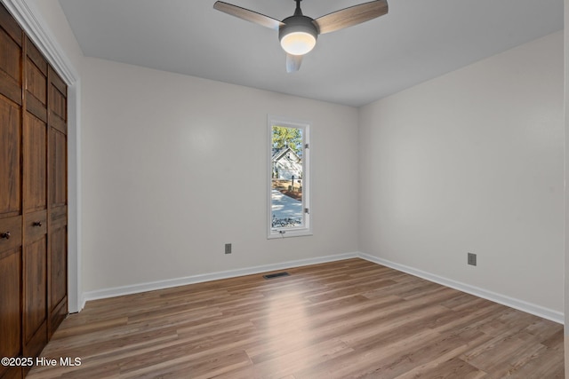 unfurnished bedroom featuring light wood finished floors, baseboards, visible vents, ceiling fan, and a closet