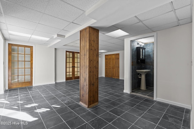 empty room featuring dark tile patterned flooring, a drop ceiling, and baseboards