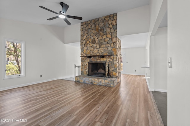 unfurnished living room featuring a ceiling fan, a fireplace, baseboards, and wood finished floors