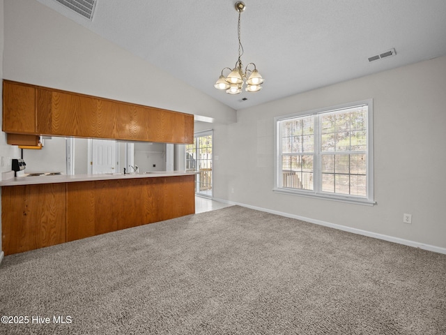 kitchen with pendant lighting, lofted ceiling, kitchen peninsula, and an inviting chandelier