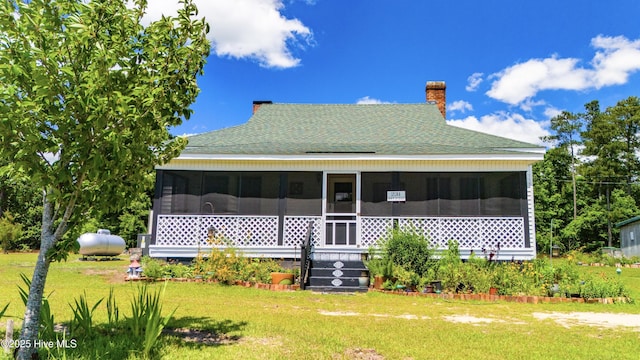 back of property with a lawn and a sunroom