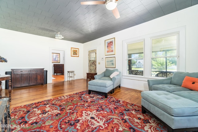 living area featuring ceiling fan, light hardwood / wood-style floors, and brick ceiling