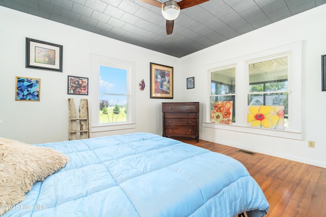 bedroom featuring crown molding, ceiling fan, hardwood / wood-style floors, and multiple windows