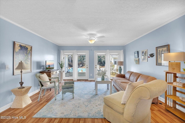 living room featuring crown molding, a textured ceiling, baseboards, and wood finished floors