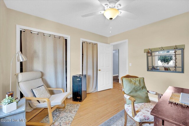 office space featuring a ceiling fan, light wood-type flooring, and baseboards