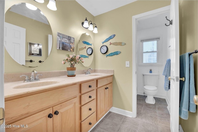 full bath with double vanity, a sink, toilet, and baseboards