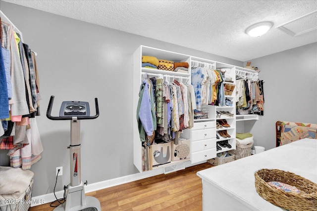 spacious closet with attic access, visible vents, and wood finished floors