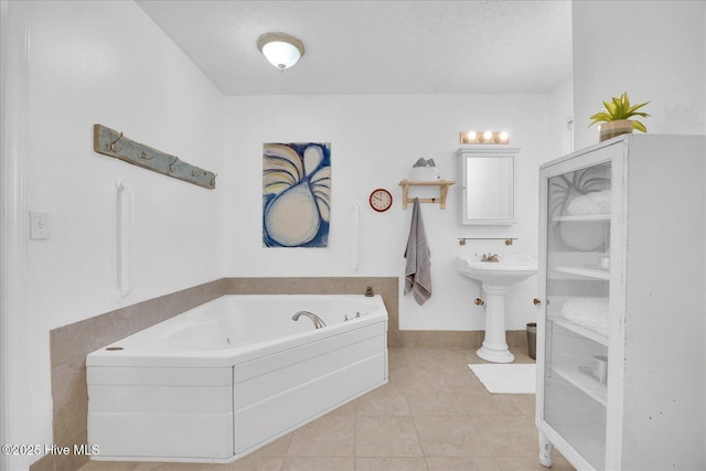 bathroom with a garden tub, a textured ceiling, and tile patterned floors